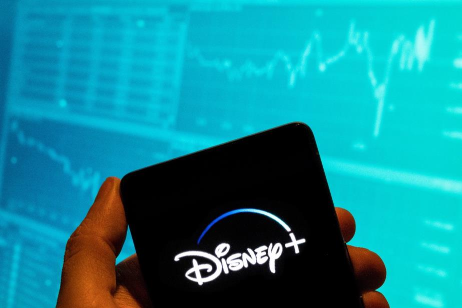 Disney+ logo on a phone, with graphs in the background