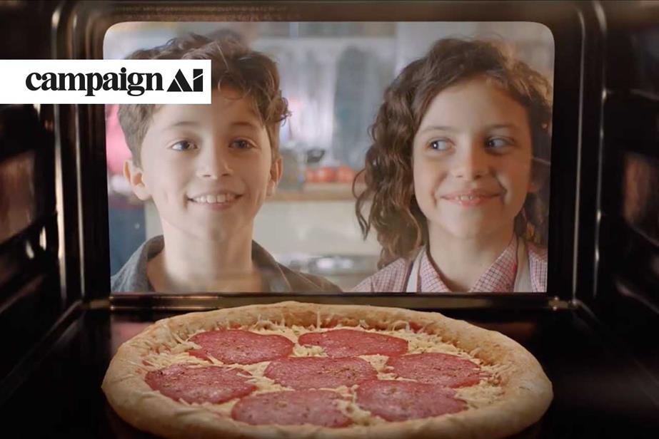 Two children watch a pizza baking in the oven